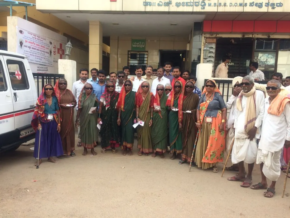 Elderly villagers wearing post-operative glasses after free cataract surgery, gathered outside the hospital