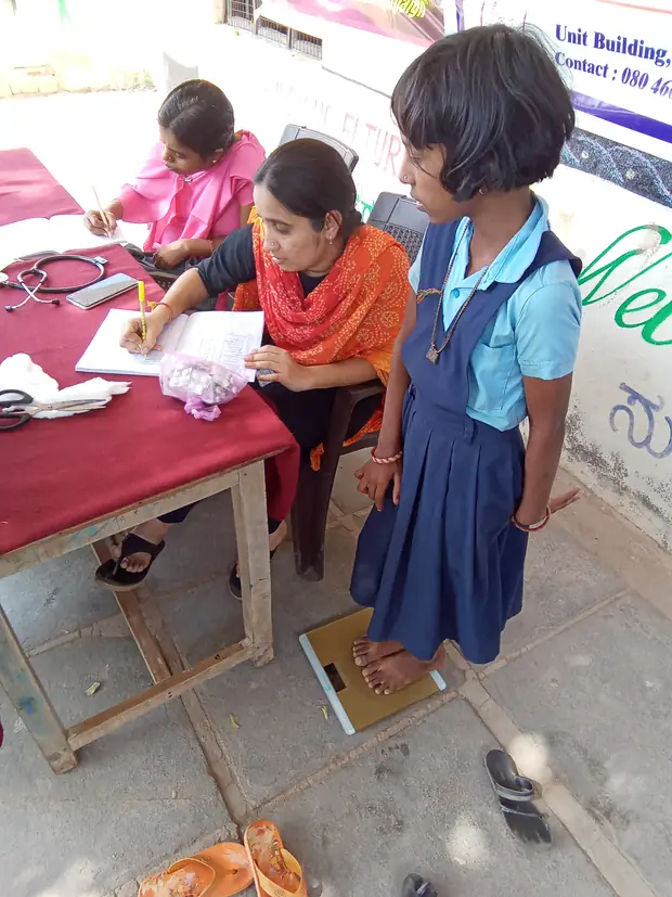 A girl is weighed and registered before vaccination.